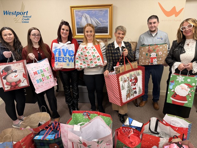 group of people holding up christmas gift bags