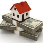 Model house sitting on bundles of cash