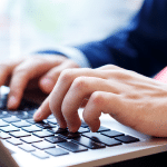 Hands typing on laptop keyboard