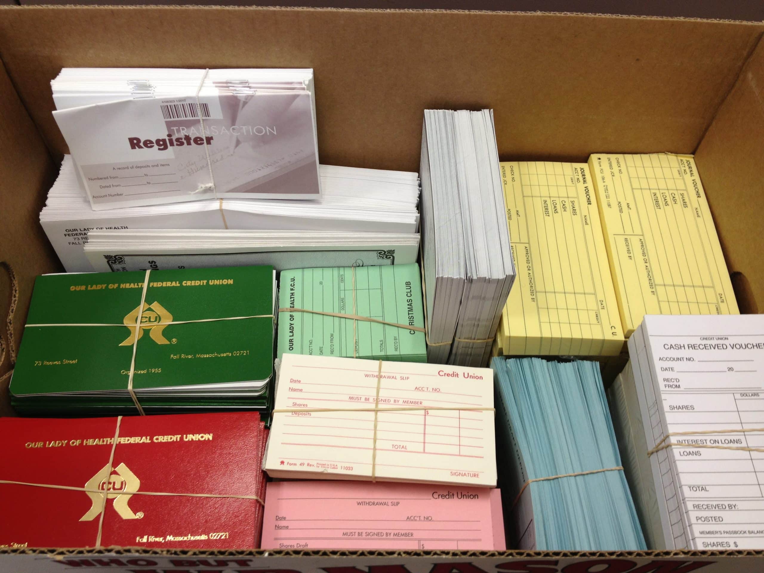 Box full of various bank forms, deposit, and withdrawal slips from multiple credit unions.